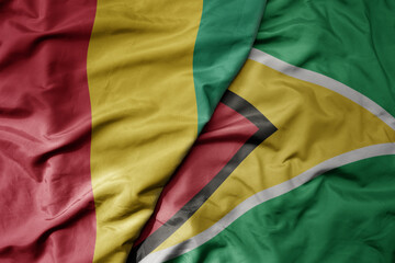 big waving national colorful flag of guyana and national flag of guinea .