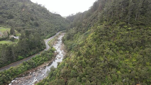 Aerial video of scenic road winding through the heart of a lush valley, alongside a river. Natural landscapes in  the majestic Karangahake gorge, New Zealand