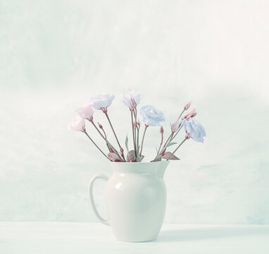 very light delicate bouquet of flowers in a jug on a light background. Interior photo in pastel colors