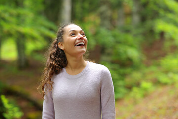 Happy casual woman looking amazed in a forest