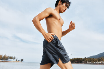 Muscular Asian Athlete Enjoying Outdoor Cardio Workout on the Beach at Sunset