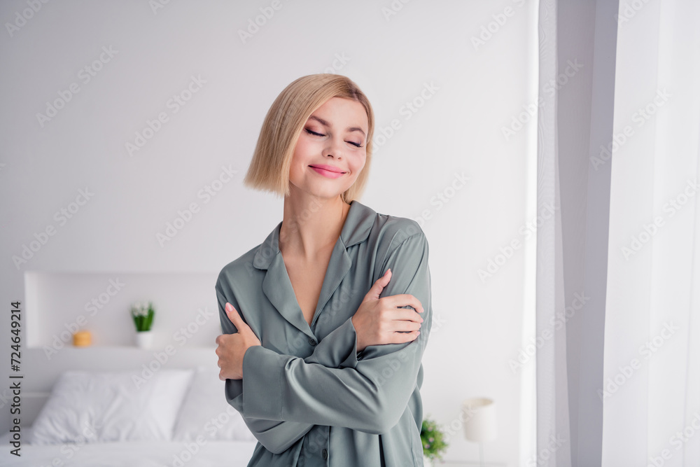 Poster photo of young beautiful blonde bob hair lady wearing soft grey nightwear sleepy mood hugging hersel