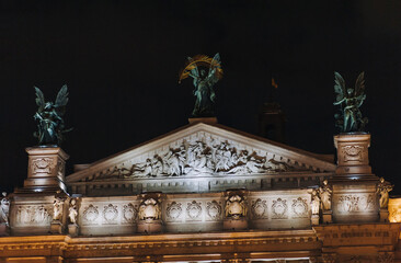 Roof of the Lviv Opera and Ballet Theater. The central sculpture is "Glory", the left one is "Music", the right one is "Comedy and Drama". Night photography with facade illumination.