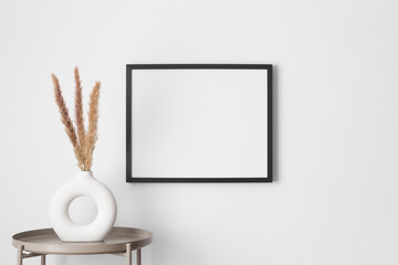 Black frame mockup on the wall with a pampas decoration.