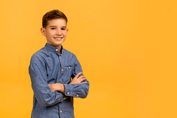 Portrait Of Handsome Teen Boy With Folded Arms Standing Over Yellow Background