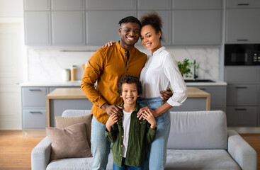 Happy black family with child smiling together in the kitchen