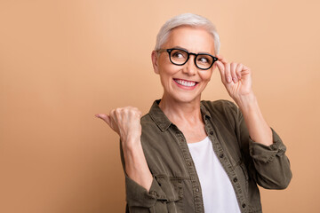 Photo of grey hair old woman wear khaki shirt direct thumb mockup touch eyewear recommend optics store isolated on beige color background