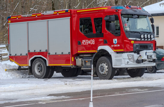 Polska Ćmielów 10 grudnia 2023 o 11:54. „Bojowy” czerwony wóz strażacki Volvo.Czerwony wóz strażacki produkcji szwedzkiej zaparkowany na zaśnieżonym parkingu.