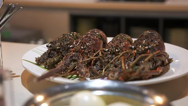 Close up of fresh uncooked spiny lobsters on a plate on the kitchen table ready to cook. The most popular seafood dishes of the Caribbean cuisine 