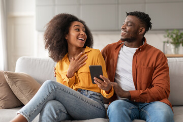african american spouses using cell phone scrolling through apps indoor