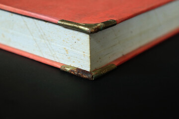 An old book with an orange cover on a black table. Old books piled up in a heap, close-up, learning and education concept.