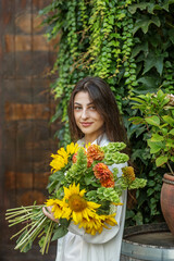 Naklejka premium Content Woman with a Bouquet of Seasonal Flowers