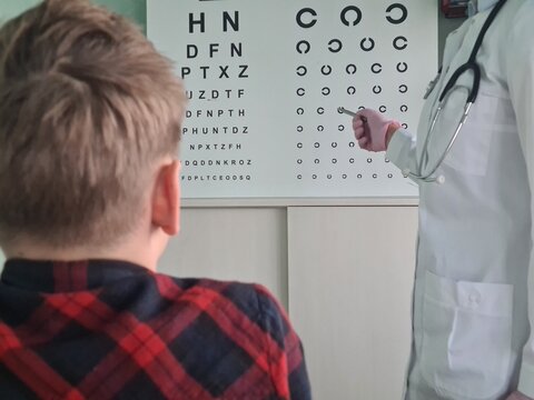 Ophthalmologist holds pen to check vision of teenage boy child