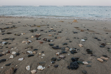lot of colorful stones and corals in the fine sand from the beach after ebb