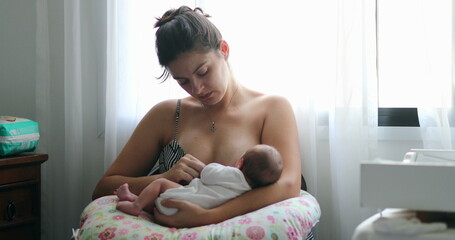 Mother breastfeeding newborn baby next to window