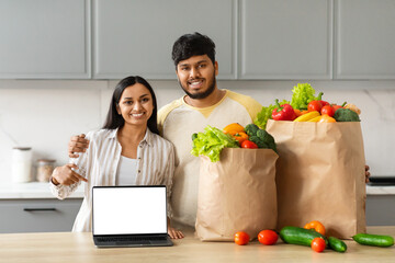 Smiling millennial eastern couple order grocery online, using laptop