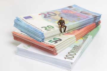 Miniature businessman navigates the financial landscape, surrounded by Euro banknotes, embodying the essence of success and prosperity on a small but impactful scale.