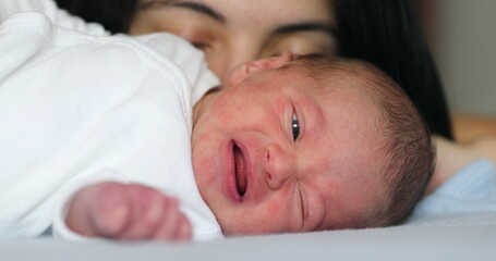 Mother next to newborn baby laying in bed