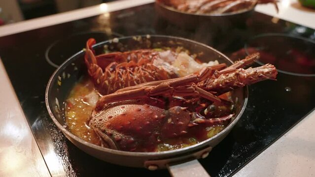 Close up of cooking spiny lobsters steaming on a frying pan on an electric stove. The most popular seafood dishes of the Caribbean cuisine 