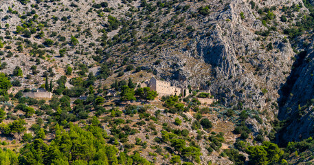 Panoramic view with old monastery on the coast of Brac island in Croatia near Bol village. Limestone mountains and mediterranean vegetation seen from a boat on a summer day in the adriatic sea.