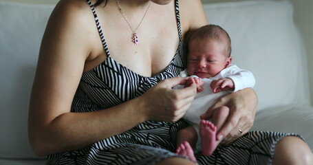 Newborn baby crying being held in mother arms