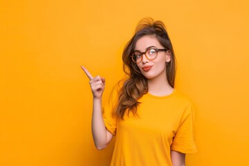 A young girl on an orange studio background gestures with her finger raised. - obrazy, fototapety, plakaty