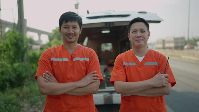 Portrait of two paramedics man. Two asian paramedic man in uniform standing with arms crossed rear of the ambulance smiling to camera. EMS Paramedic