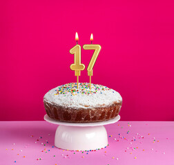 Lighted birthday candle number 17 - Birthday card on pink background