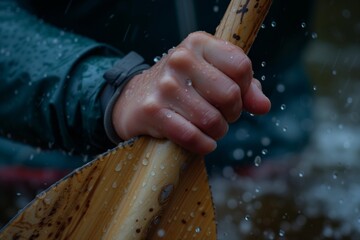 close up of hands holding paddle, water droplets visible