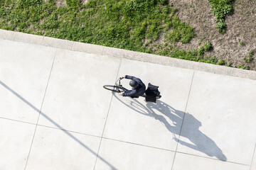 Cyclist with helmet riding a electric bicycle on a concrete way. Copy space. Aerial view