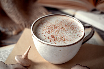 A cappuccino cup on the table in close-up. Coffee with milk in the middle of books