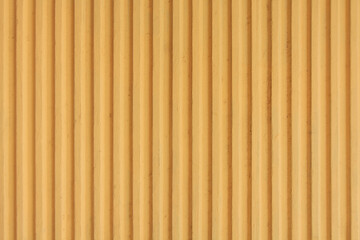 Old mustard yellow concrete background wall with vertical line ribbed. Stripes as a texture.