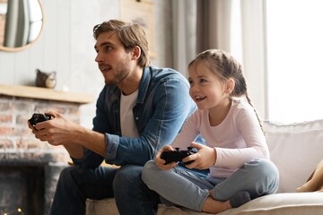 Young man and little girl playing computer game with gaming console. - Powered by Adobe