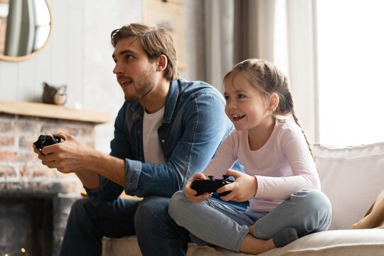 Young Man And Little Girl Playing Computer Game With Gaming Console.