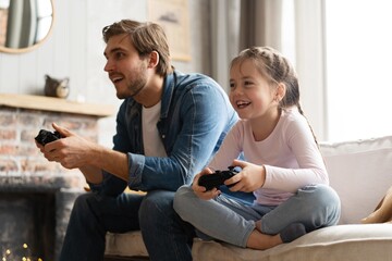 Young man and little girl playing computer game with gaming console. - obrazy, fototapety, plakaty