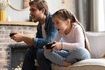 Young man and little girl playing computer game with gaming console.