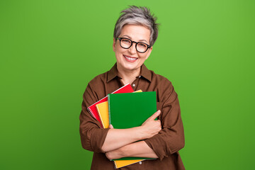 Photo of positive woman with short haircut wear brown shirt in glasses embrace copybooks smiling...