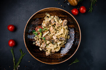 Lunch linguini pasta with chicken, mushrooms, tomatoes, spices and greens.