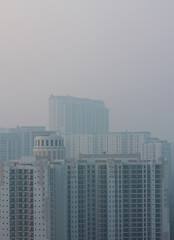 Obraz premium Foggy winter evening in Gurgaon,Haryana,India. Luxury residential apartments and commercial buildings with urban,modern architecture. Gurugram,Delhi NCR cityscape with dense fog at Sunset,