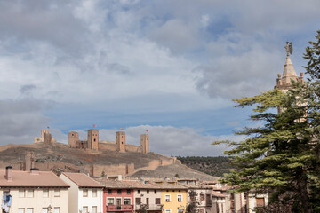 a picturesque scene of an old town with colorful buildings and a historic castle under a bright, partly cloudy sky