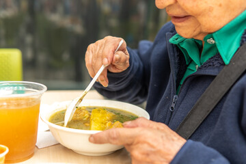 Unrecognizable senior woman having a soup
