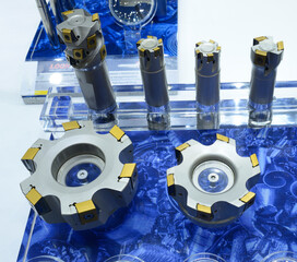 Modern double-sided inserts with long helical cutting edges, for milling, presented on stand.