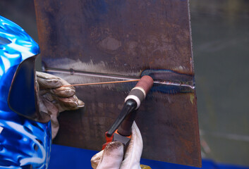 welder welding two pieces of metal using argon torch and filler rod, argon welding