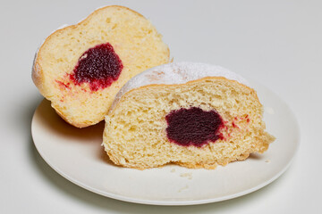 donut filled with fruit jam and powdered sugar on top.