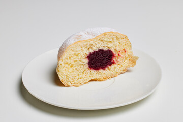 donut filled with fruit jam and powdered sugar on top.