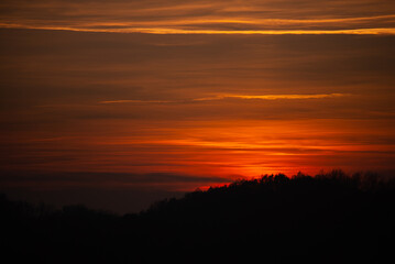 Fototapeta na wymiar Orange solar disk seen above the forest. Wonderful sunset at the end of day