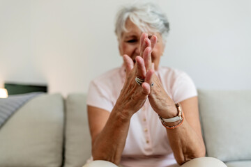 Unhappy senior old hoary woman touching wrist joint, suffering from injured hand. Frustrated...