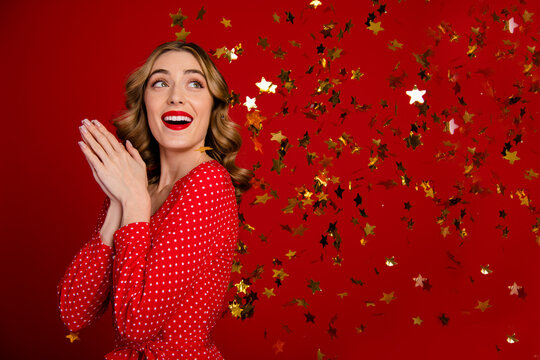 Photo of lovely stunning girl look empty space flying star shape confetti isolated on red color background