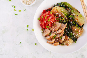 Stir fried of chicken, sweet peppers and bok choy in a bowl on the table. Stir fry pak choi. Asian food. Top view