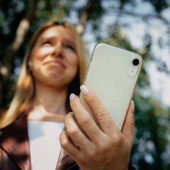 Young caucasian girl with wireless headphones in the park using tablet, phone and smiling